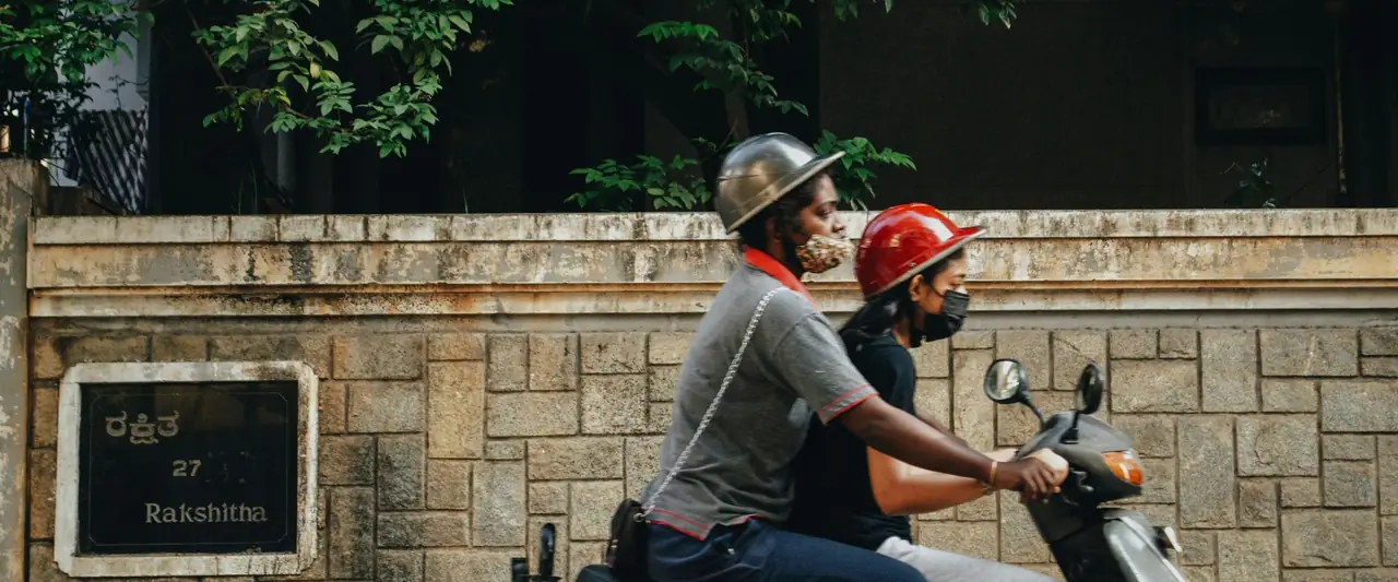 Two people riding a scooter on a city street