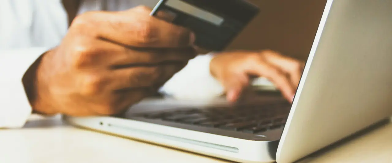 Person paying online with a credit card and laptop